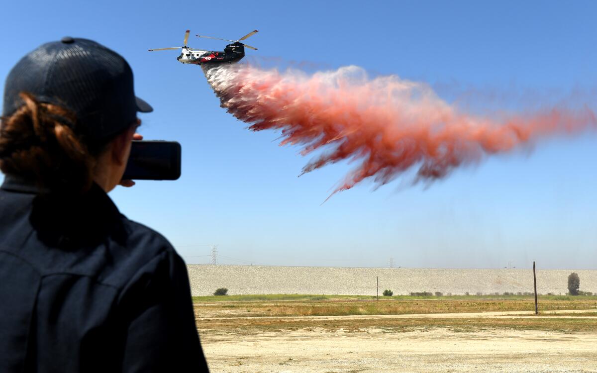 A helicopter drops pink fire retardant