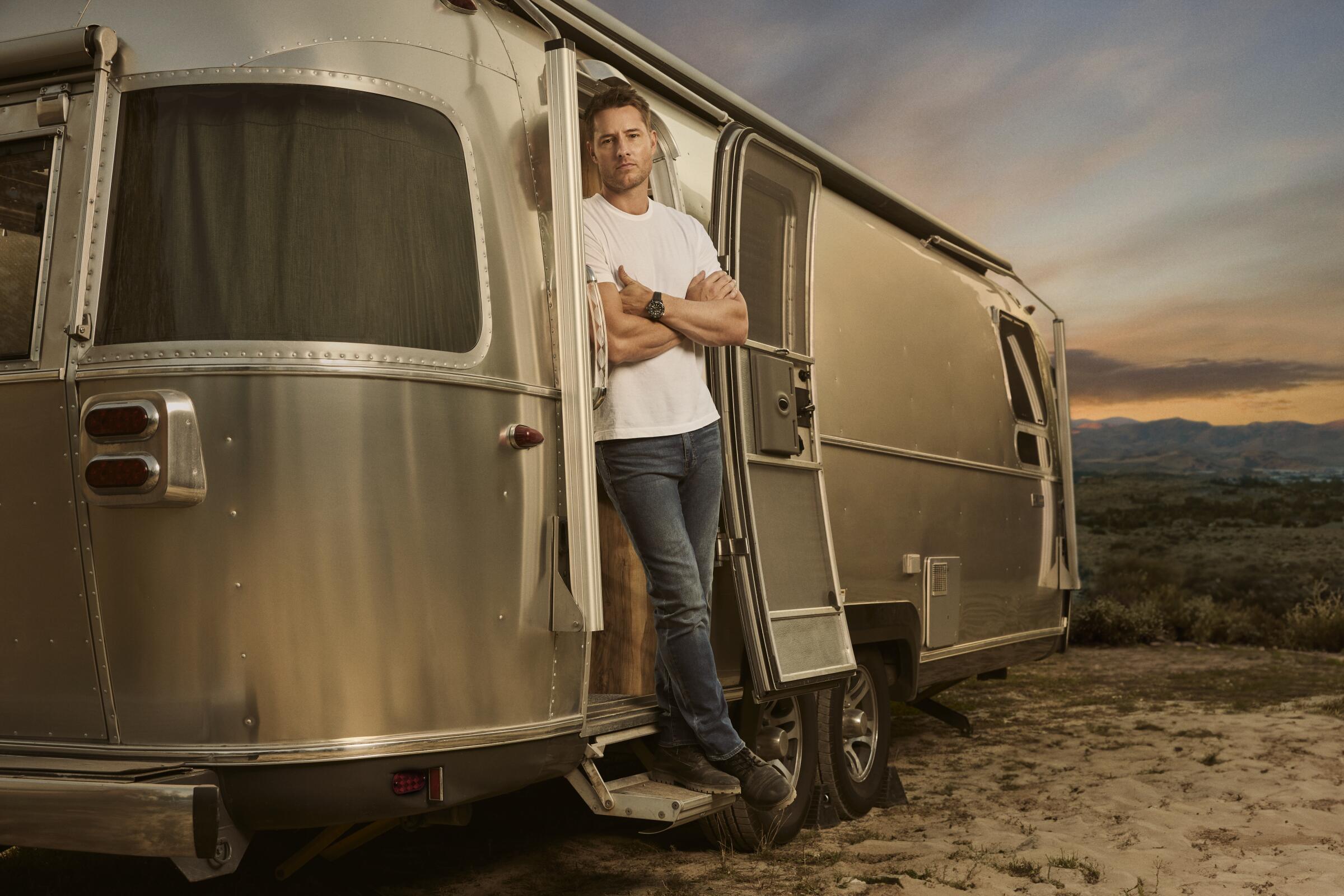 A man stands in the doorway of an airstream.