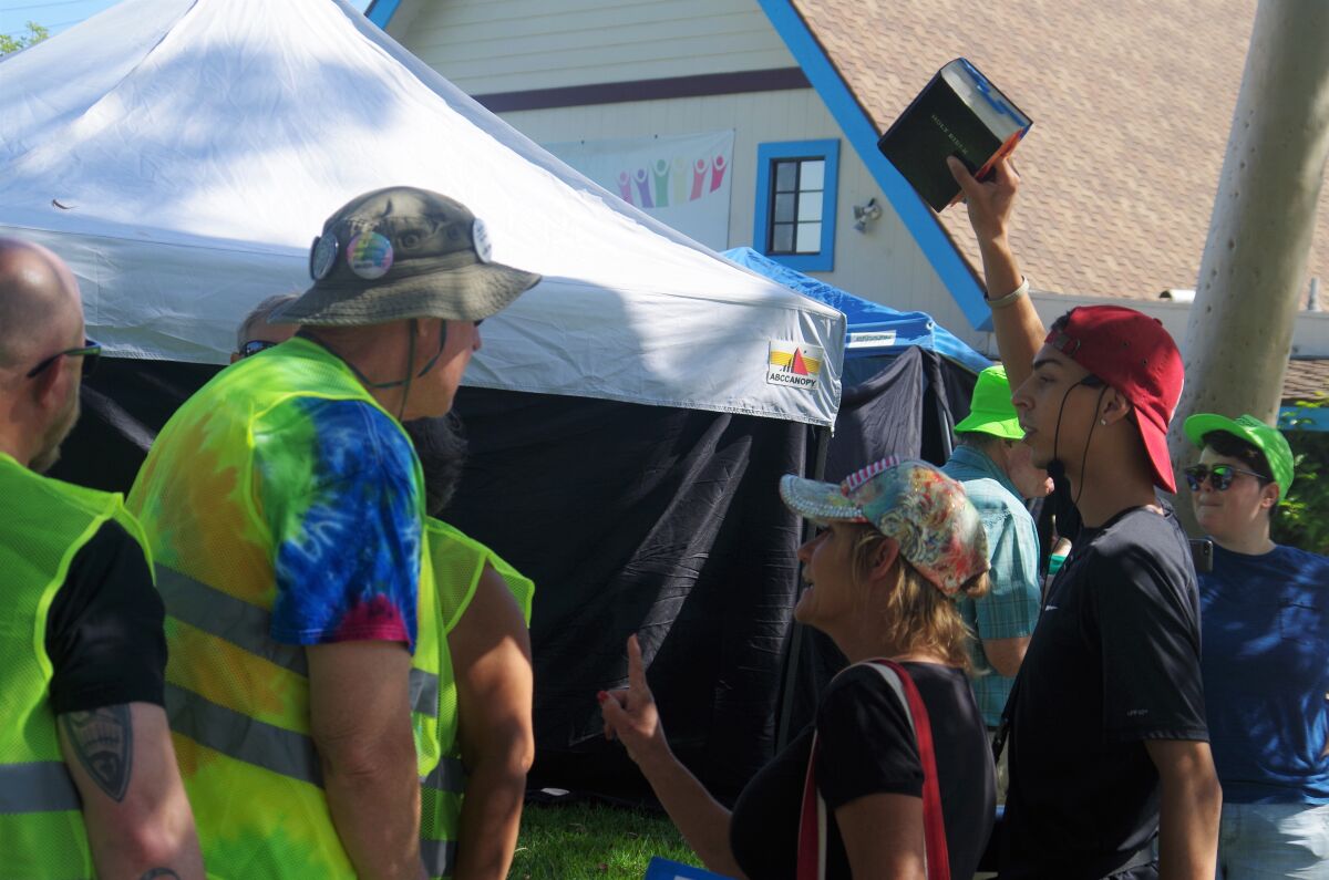 Protesters approach security guards and legal observers, wearing neon, outside a drag queen story time on Saturday at Fairview Community Church in Costa Mesa.