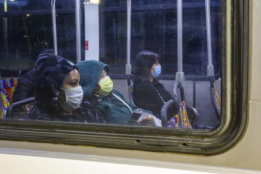 EL MONTE, CA - MARCH 20, 2020 - On the first day of LA's 'Safer at Home.' some commuter protect themselves with a face mask while riding a bus at El Monte Metro Station. (Irfan Khan / Los Angeles Times)