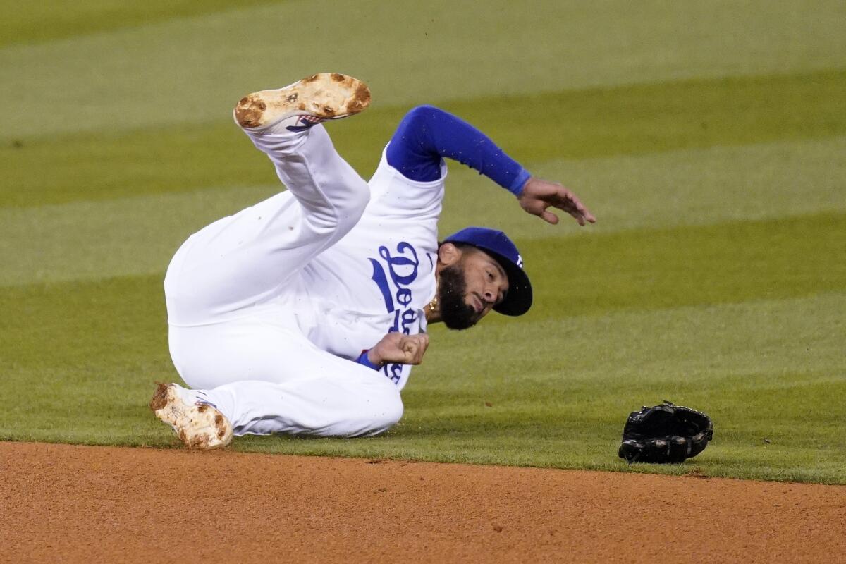 Los Angeles Dodgers third baseman Edwin Rios loses his glove after diving for a ball hit for a single by Cincinnati Reds.
