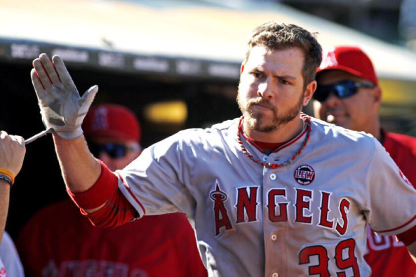 Angels left fielder J.B. Shuck high-fives teammates after scoring against the A's in the 11th inning on Wednesday.