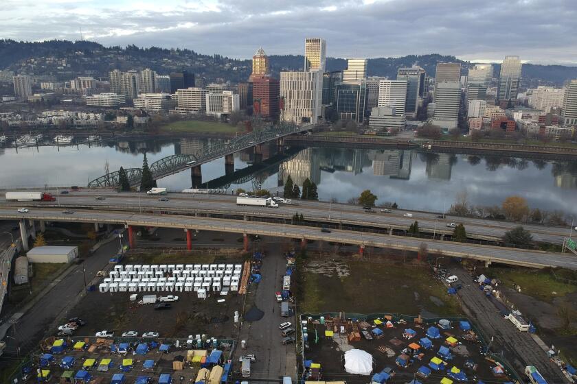 FILE - In this aerial photo taken with a drone, tents housing people experiencing homelessness are set up on a vacant parking lot in Portland, Ore., on Dec. 8, 2020. Voters in Portland, Ore., have approved a ballot measure that would completely overhaul City Hall, amid growing public frustrations over homelessness and crime. The measure will scrap the city's unusual commission form of government and replace it with a more traditional city council. (AP Photo/Craig Mitchelldyer, File)