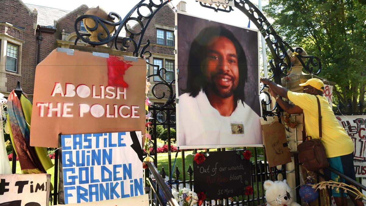 King Demetrius Pendleton hangs a sign on the gate of the governor's residence in St. Paul, Minn., as protesters demonstrate against the shooting death of Philando Castile by a police officer, Jeronimo Yanez, during a traffic stop in Falcon Heights, Minn.