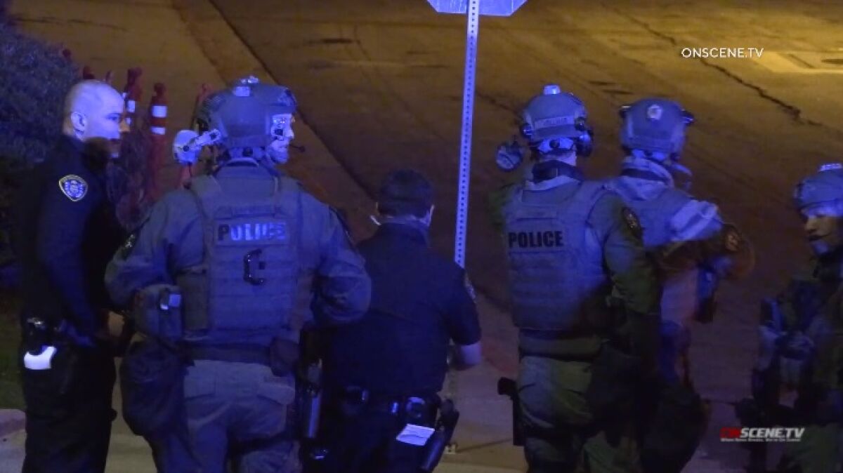 SWAT officers gather on a street corner near San Diego High School, where a wanted man was holed up in a trash bin.