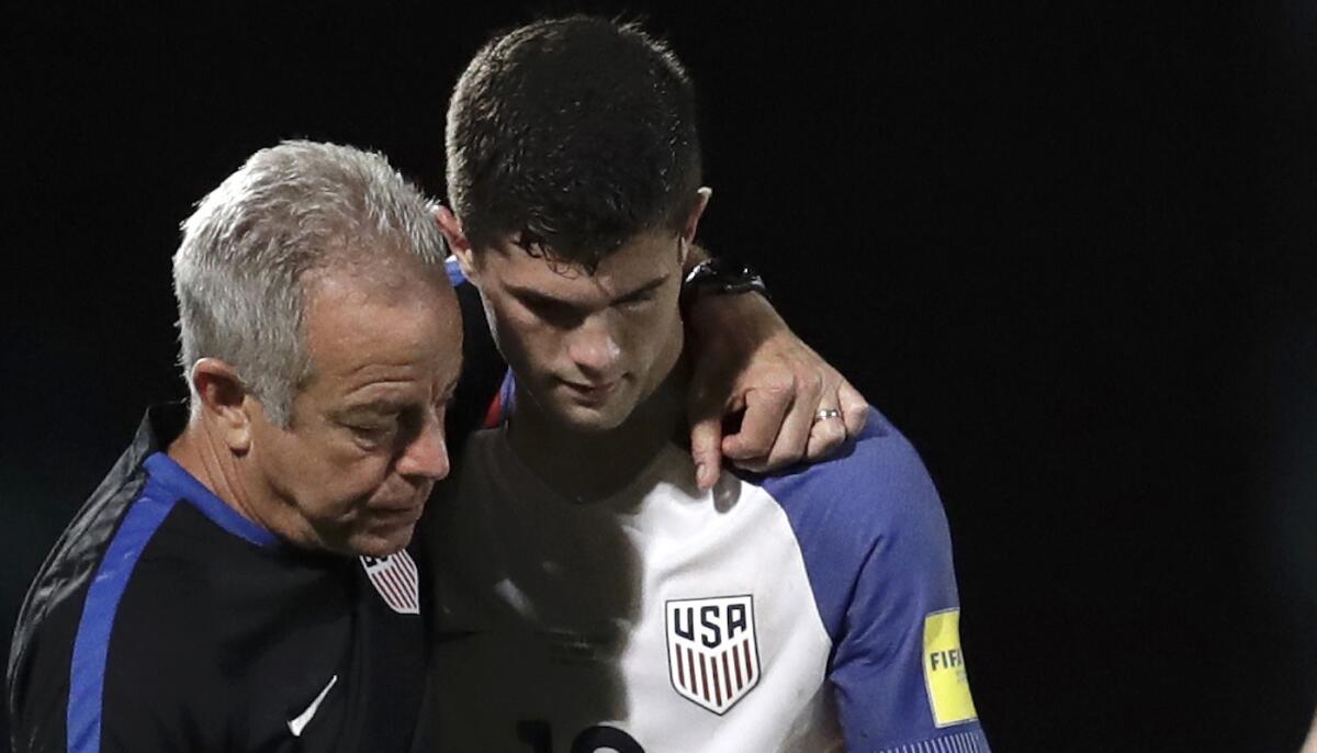 El atacante de EEUU, Christian Pulisic (d), es reconfortado por un miembro del cuerpo de entrenadores luego que el equipo quedó fuera de la Copa del Mundo Rusia 2018.
