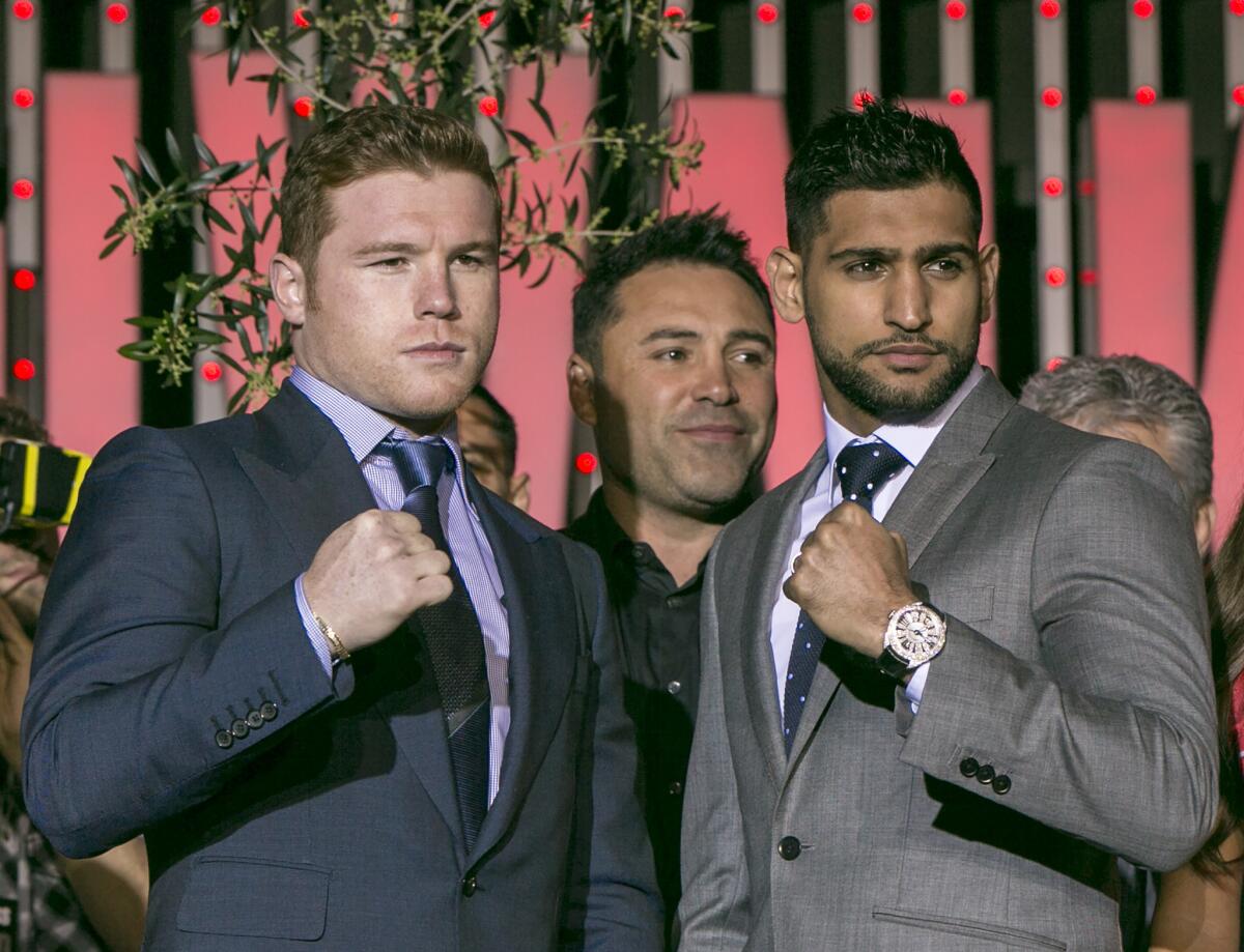 Boxers Canelo Alvarez, left, and Amir Khan, right, pose for a photo with promoter Oscar De La Hoya in Los Angeles on March 2. The boxers are scheduled to fight on May 7 in Las Vegas for Alvarez's WBC middleweight title.