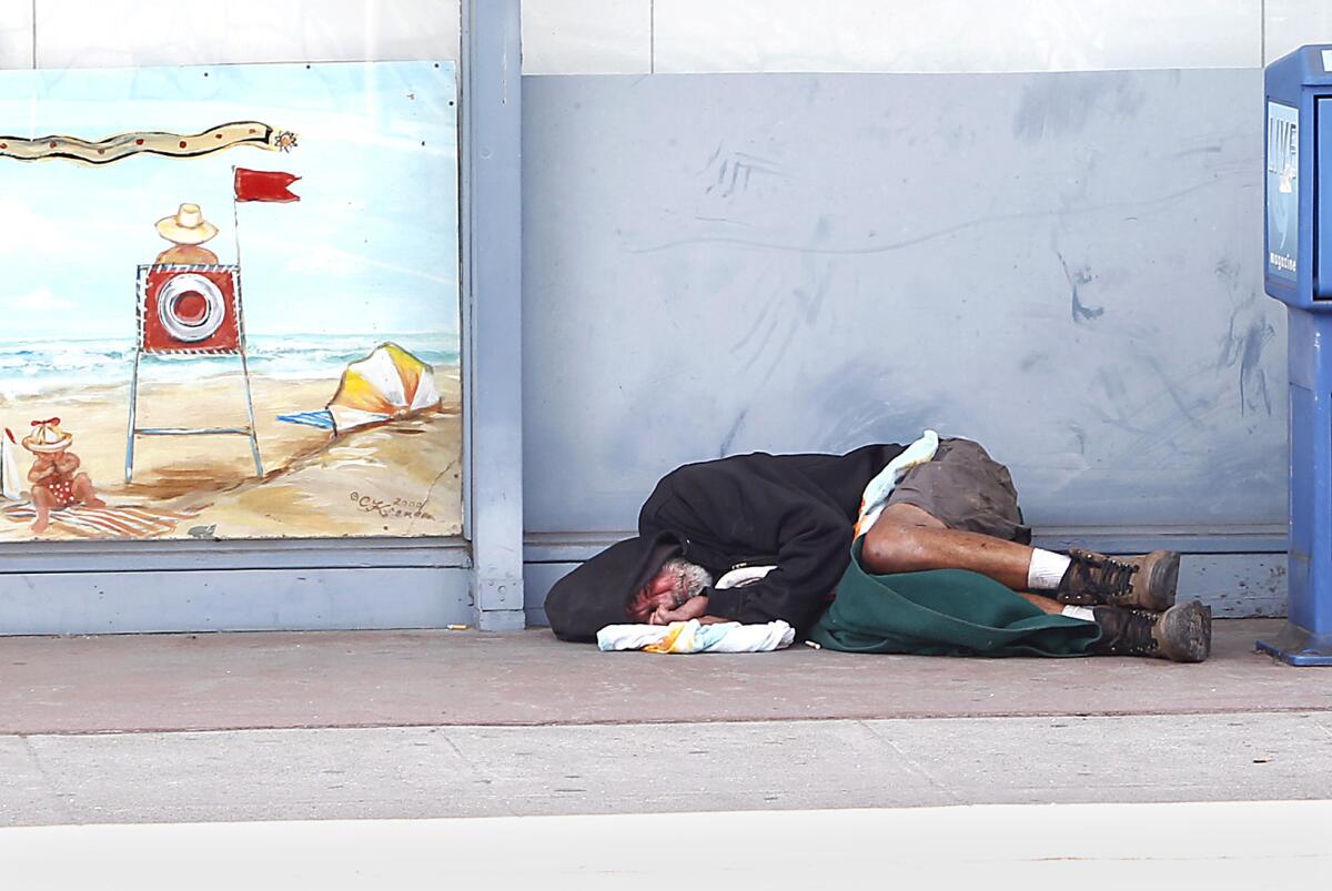 A man sleeps on the curb at Mountain Road and South Coast Highway in Laguna Beach in 2014.