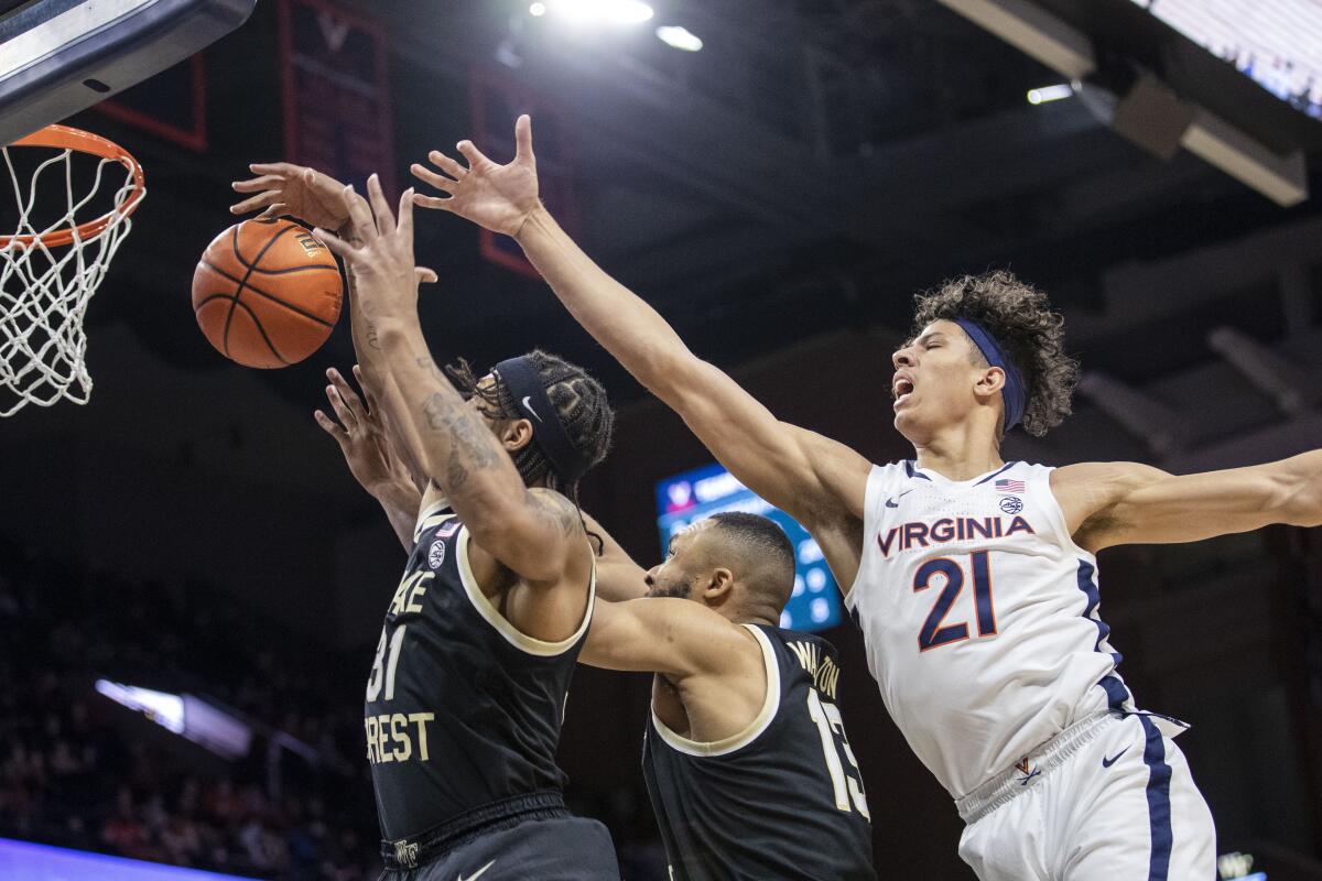 Wake Forest guard Alondes Williams (31) and forward Dallas Walton (13) block Virginia forward Kadin Shedrick (21) from a rebound during the second half of an NCAA college basketball game in Charlottesville, Va., Saturday, Jan. 15, 2022. (AP Photo/Erin Edgerton)