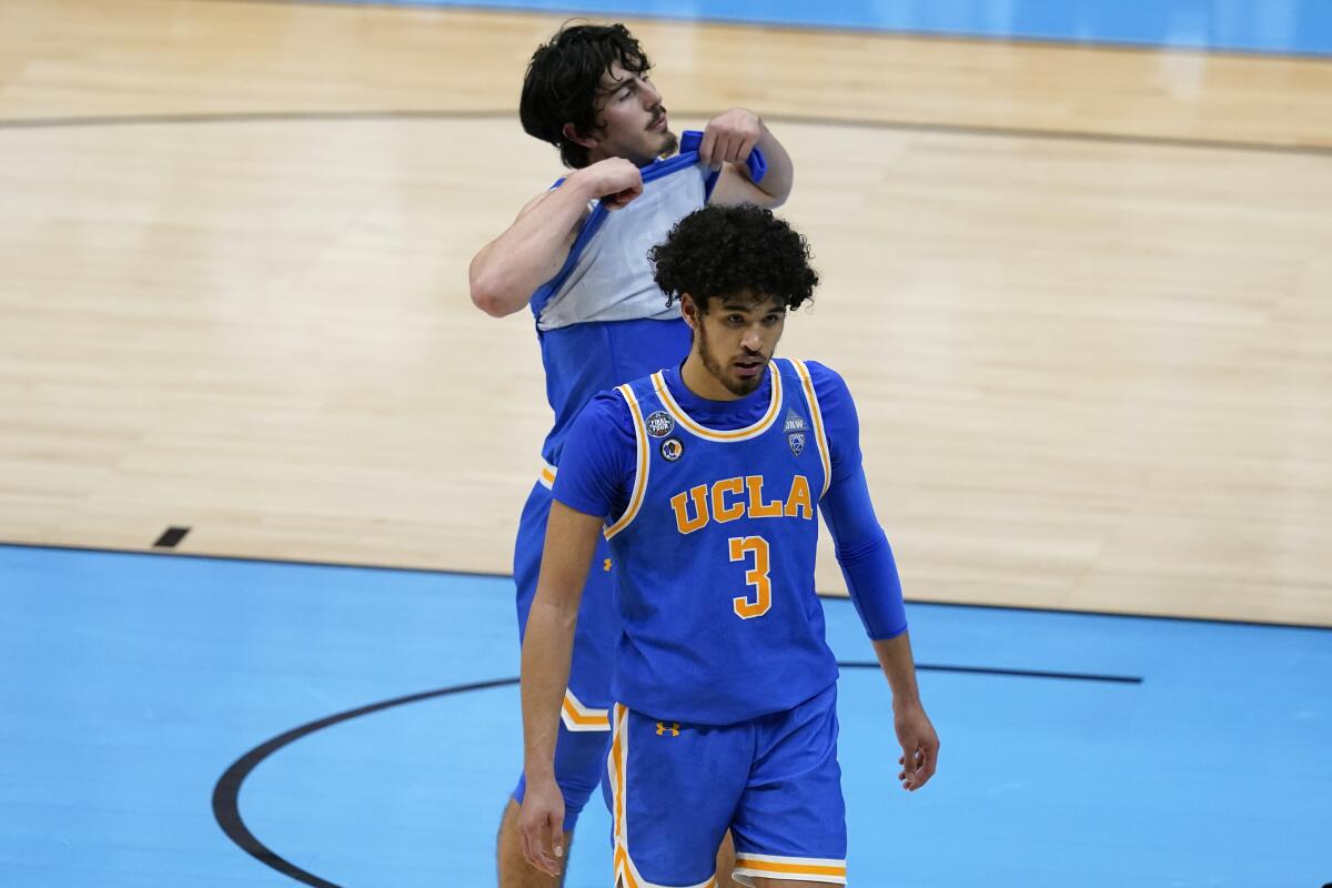 UCLA guards Johnny Juzang, front, and Jaime Jaquez Jr. walk off the court after losing in overtime to Gonzaga.