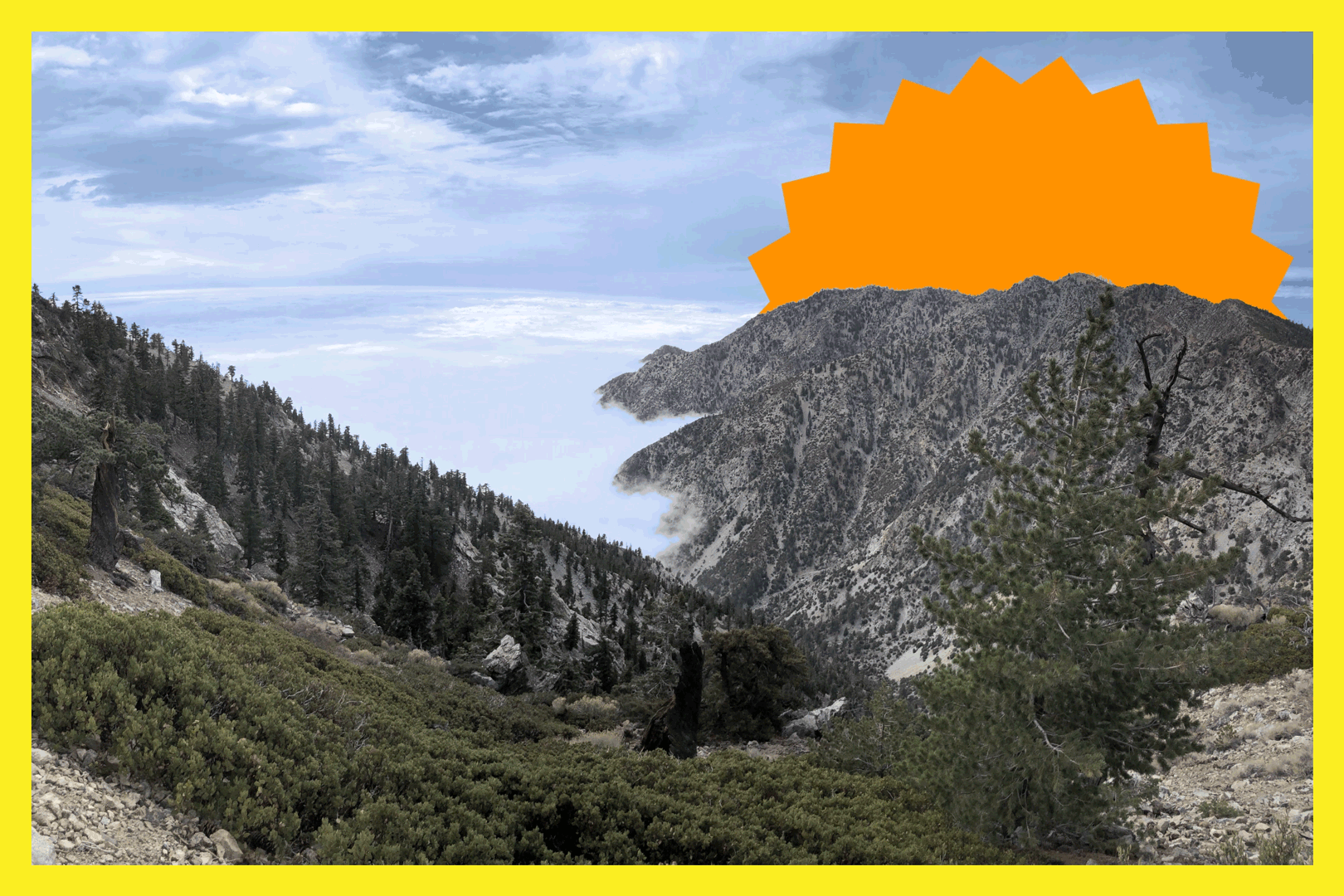 A view from the trail to Cucamonga Peak. A mountain stretches out into a valley of fog with cloudy blue skies above.