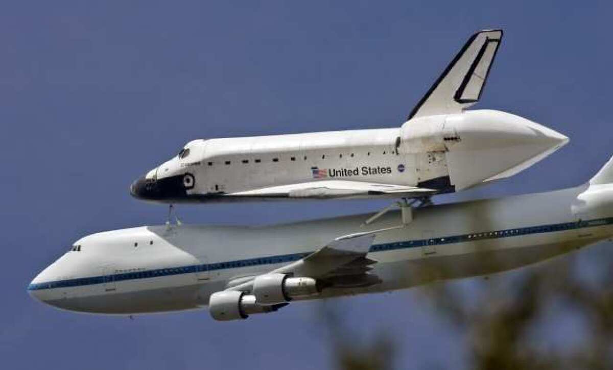 The space shuttle Endeavour on top of a transport 747 banks over the La Canada High School football field after a pass over JPL during it's trip to LAX on Friday, September 21, 2012.