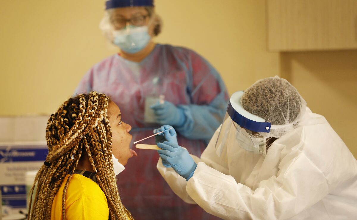 Destiny VanSciner, 32, left, gets an oral swab test for the novel coronavirus at a walk-in coronavirus testing site in South Los Angeles.