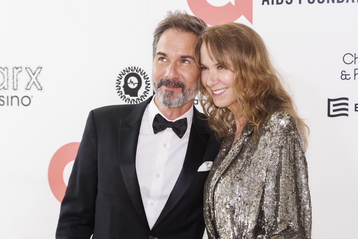 Eric McCormack, clad in a tuxedo, and presses his face close to Janet McCormack, clad in a silver sequined dress