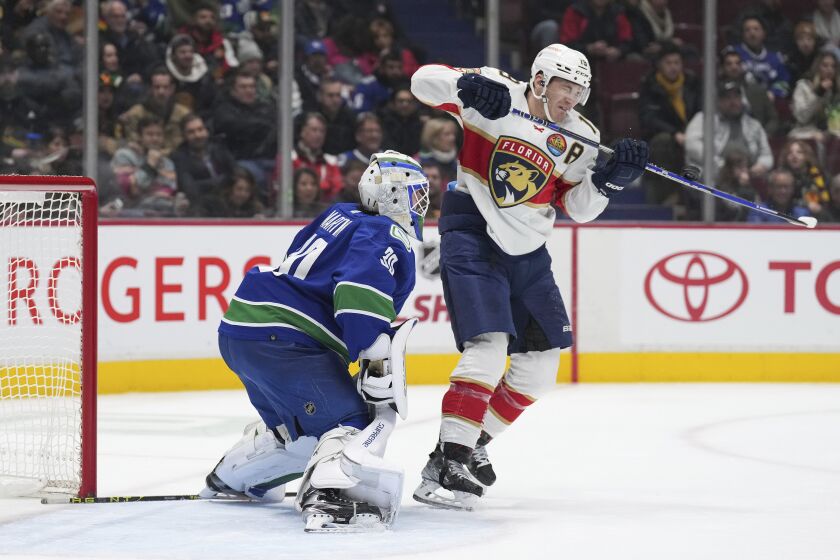 Florida Panthers' Matthew Tkachuk, right, deflects the puck wide of the net behind Vancouver Canucks goalie Spencer Martin (30) during the second period of an NHL hockey game Thursday, Dec. 1, 2022, in Vancouver, British Columbia. (Darryl Dyck/The Canadian Press via AP)