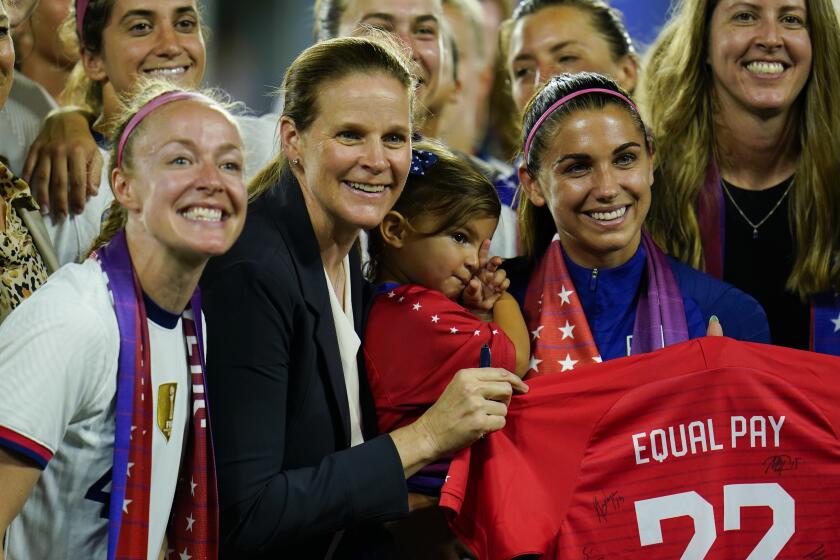 Americans Becky Sauerbrunn, Cindy Parlow Cone and Alex Morgan, shown holding her daughter, pose for  a photo