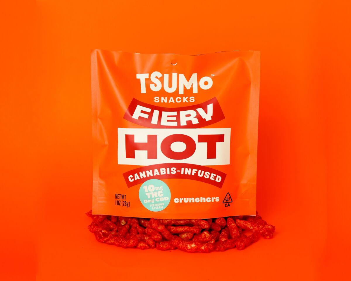 A square orange bag with bold lettering atop a pile of savory snacks