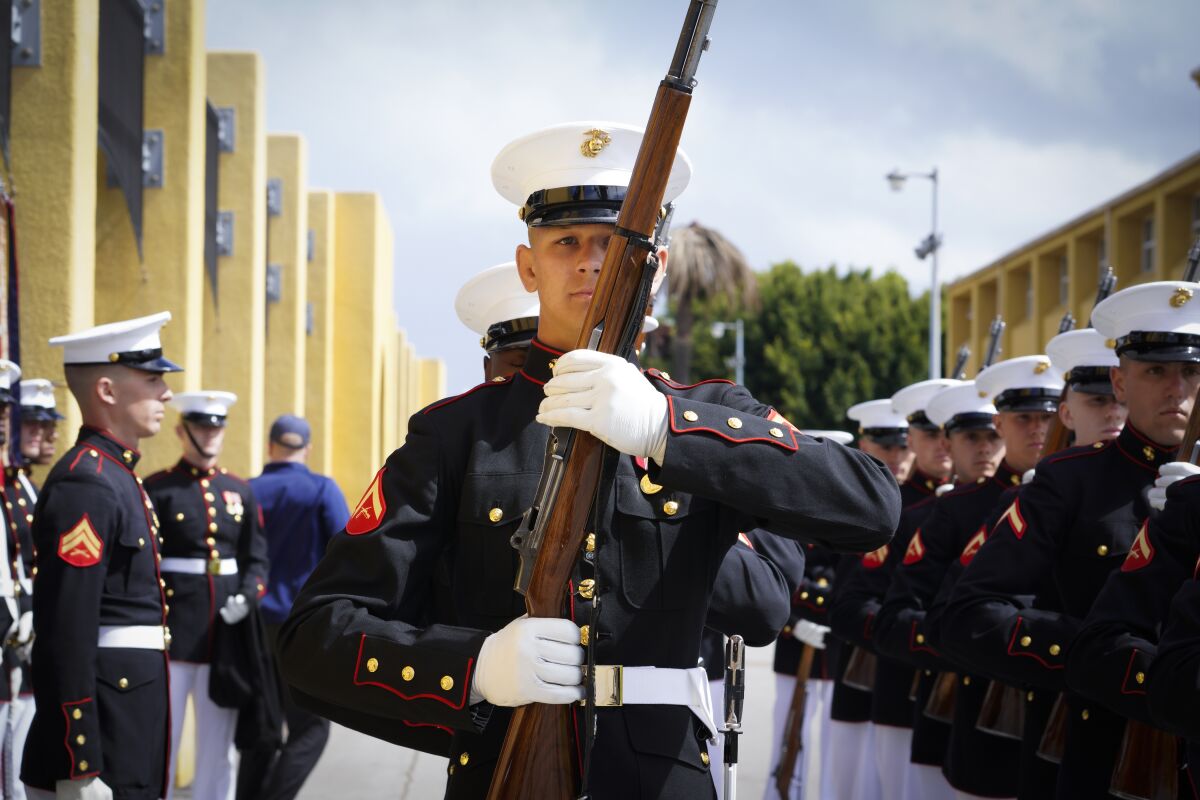 The Silent Drill Platoon in dress uniform, some carrying rifles, prepares to perform outdoors