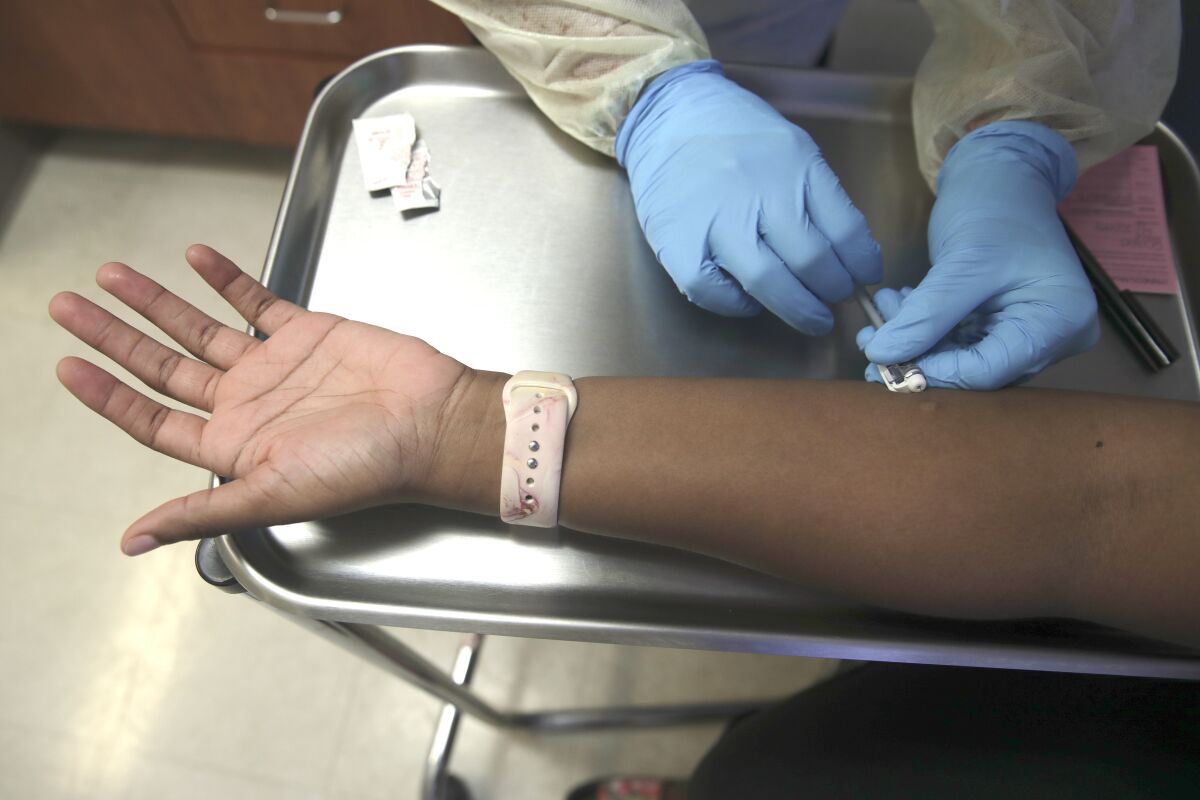 A medical worker injecting vaccine into a person's forearm