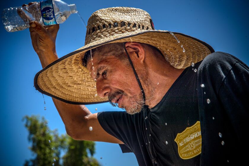 THERMAL, CA - JULY 11: Sergio Lopez, 45, working around his mobile home under blazing sun cools off by pouring cold water over on his head Oasis Mobil Home Park on Tuesday, July 11, 2023 in Thermal, CA. (Irfan Khan / Los Angeles Times)