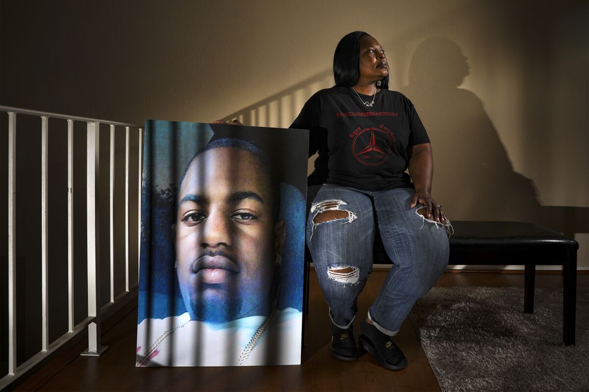 Tommy Twyman sits on a bench in her home, holding a large portrait of her son Ryan Twyman, who was killed by deputies