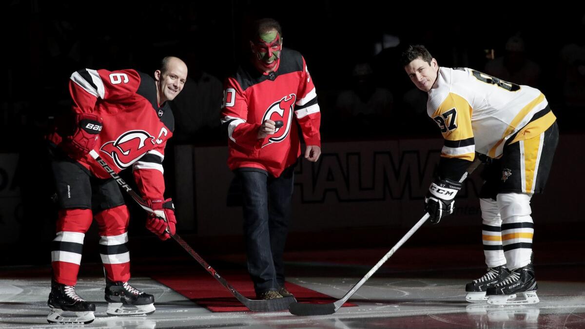 Patrick Warburton, reprising his David Puddy role from "Seinfeld," prepares to drop the ceremonial first puck for Andy Greene of the Devils, left, and Sidney Crosby of the Penguins.