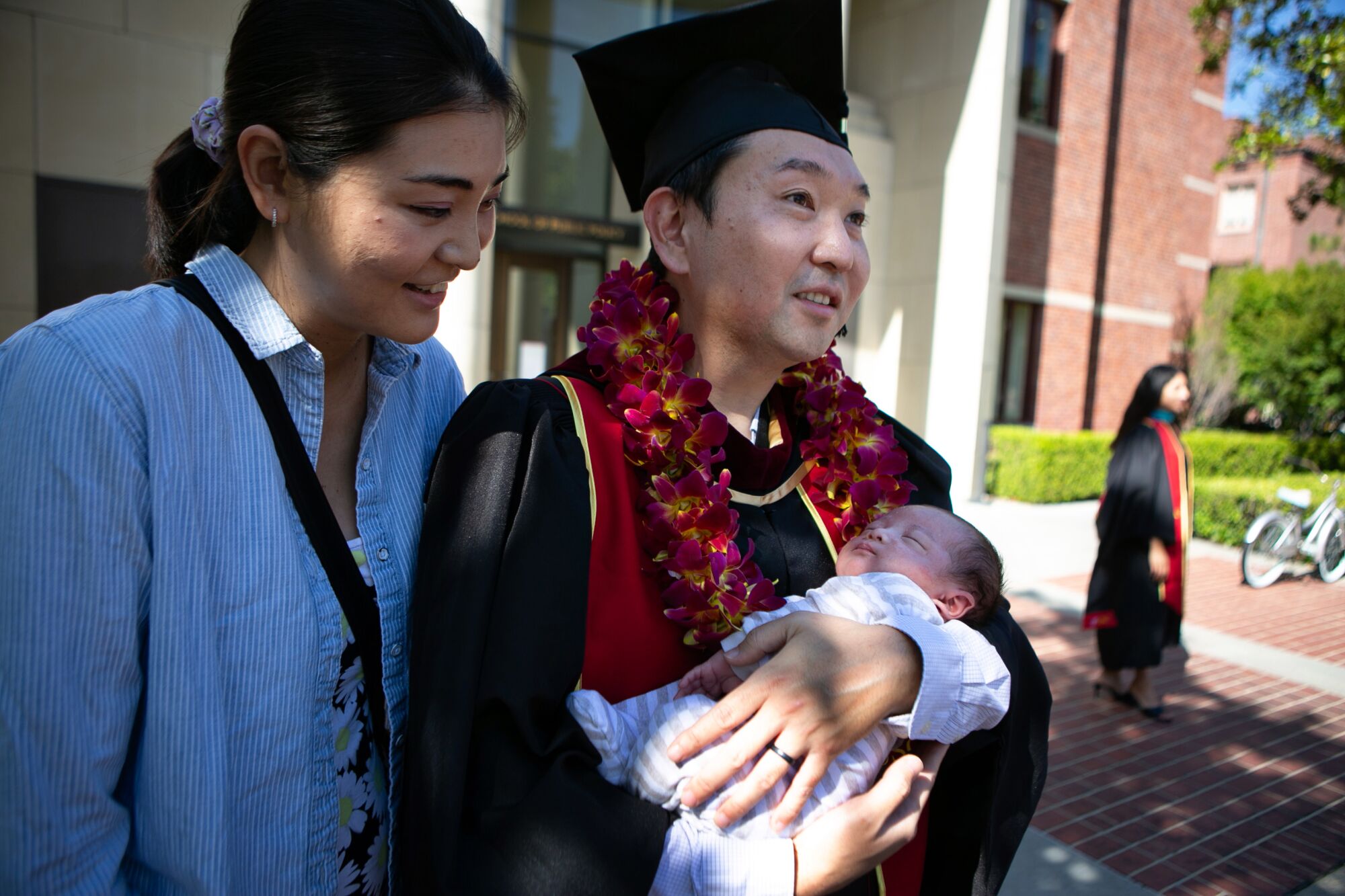 A man holds a baby as a woman looks on