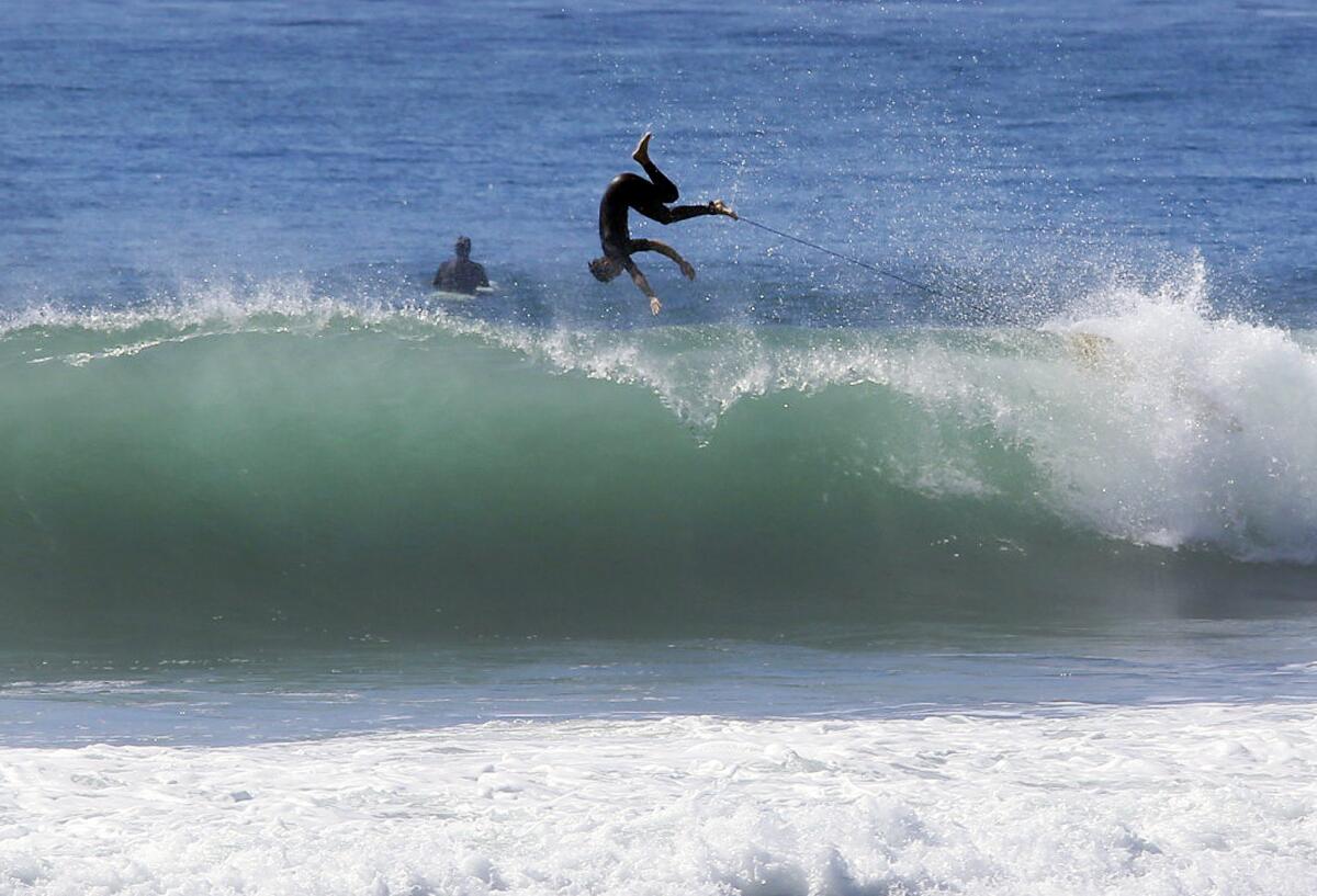 A surfer catches air while riding waves near the Malibu Pier during a high-surf advisory on Aug. 27, 2014.