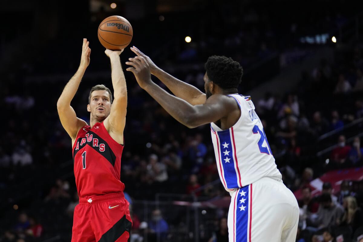 Toronto Raptors' Goran Dragic, left, goes up for a shot against Philadelphia 76ers' Joel Embiid during the first half of a preseason NBA basketball game, Thursday, Oct. 7, 2021, in Philadelphia. (AP Photo/Matt Slocum)