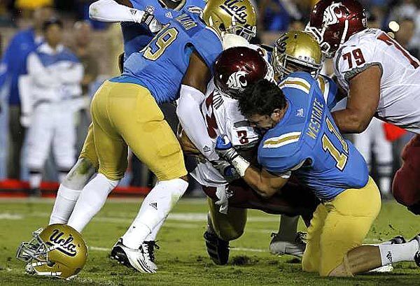 UCLA linebacker Sean Westgate, despite losing his helmet, helps bring down Washington State running back Carl Winston in the first quarter Saturday at the Rose Bowl.