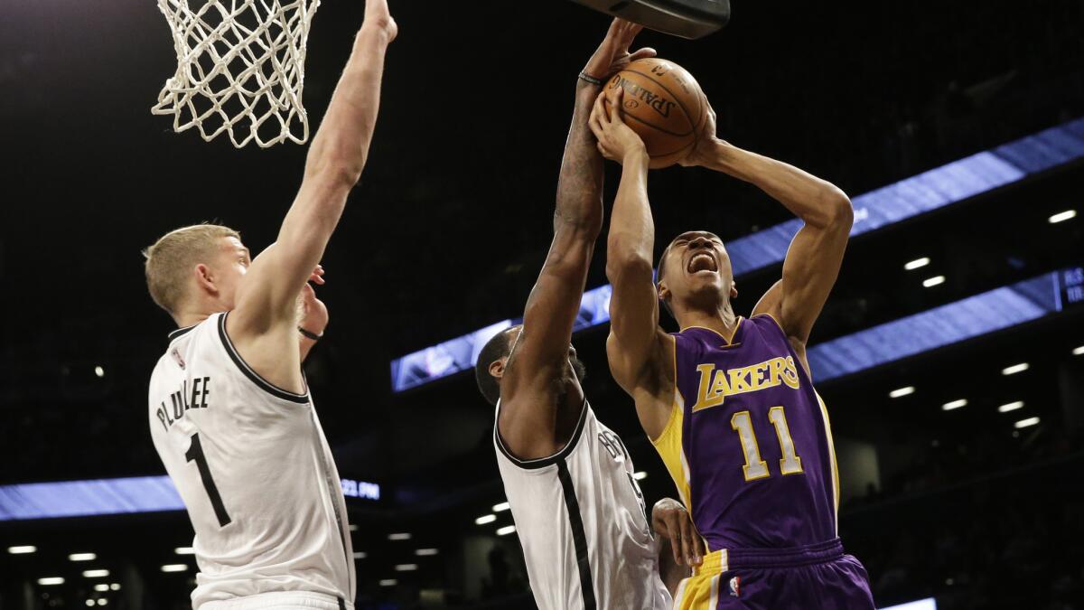 Lakers forward Wesley Johnson, right, puts up a shot in front of Brooklyn Nets teammates Earl Clark, center, and Mason Plumlee during the first half of Sunday's game.