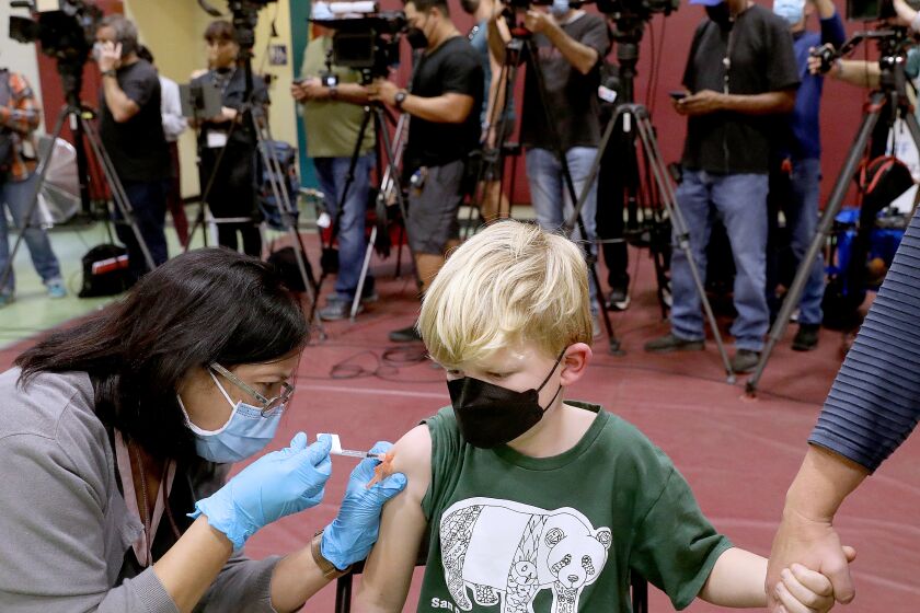 Felix Johnstone, 7, of Altadena, with mother Caitlin Johnstone, right, receives a child's dose of the Pfizer vaccination.