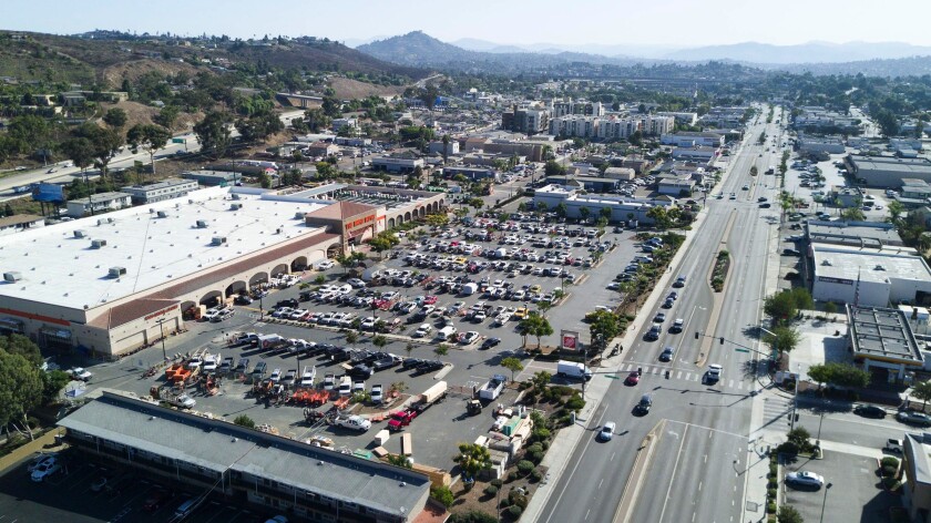 A store's parking lot filled with cars off a two-way street are shown in an aerial view. 