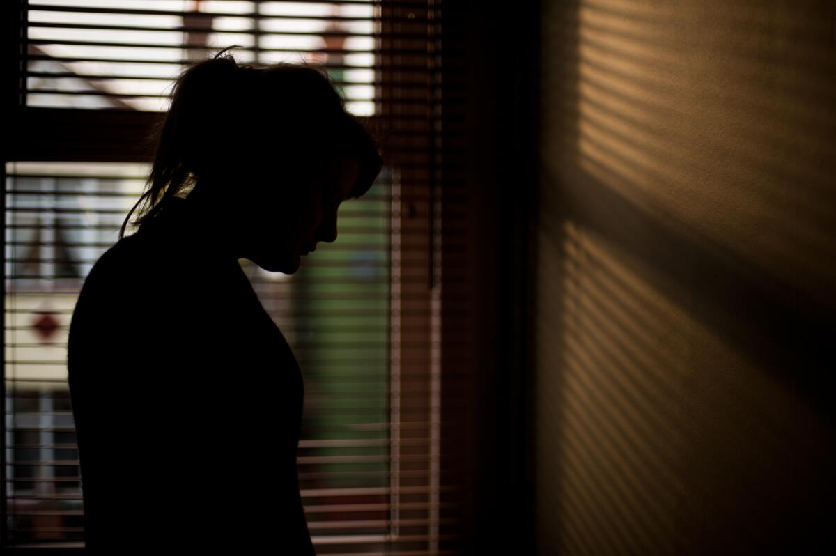 Silhouette of a woman standing by a window.