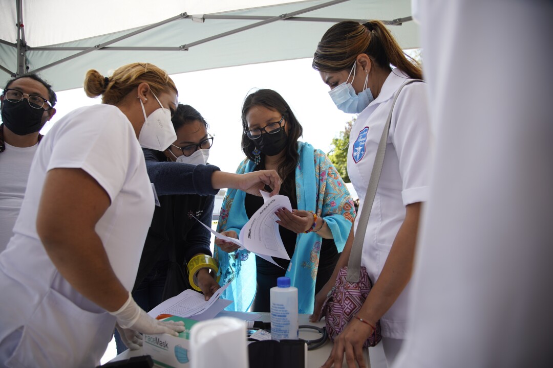 Dulce Garcia speaks with a group of medical personnel under a tent