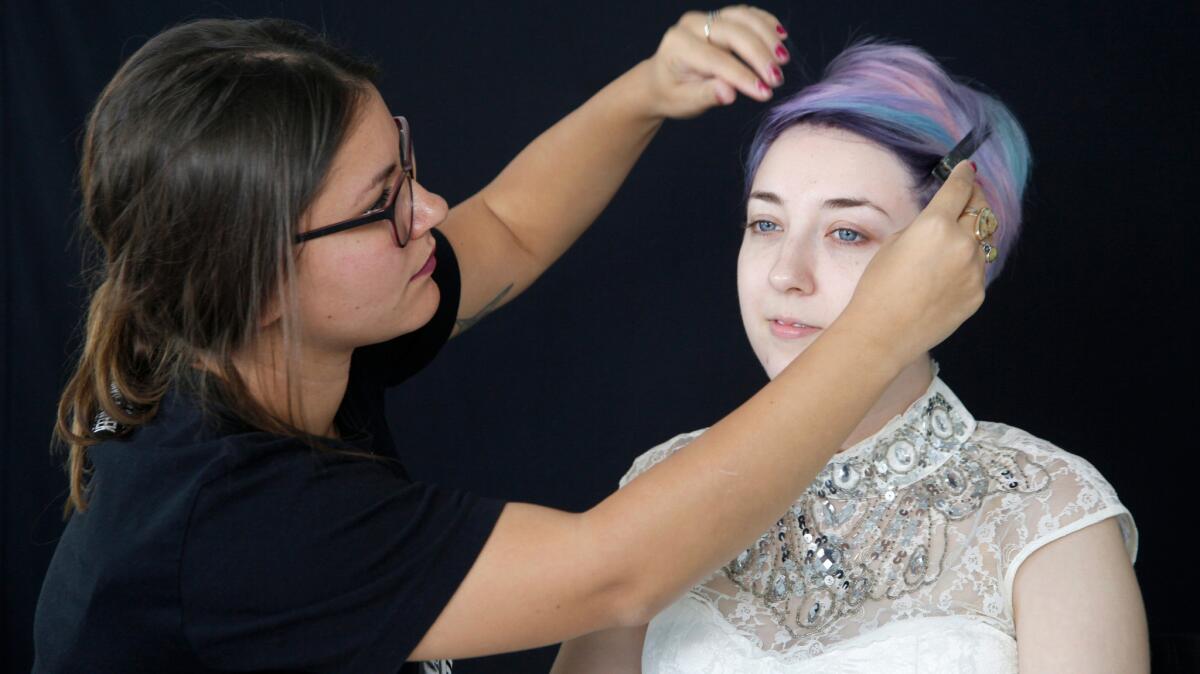 Makeup artist Amber Talarico pins back Kota Wade's hair.