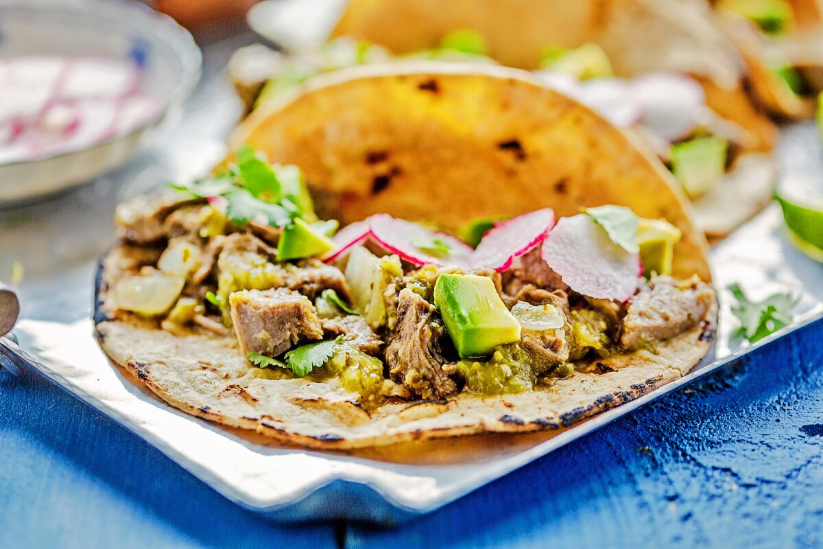 A home-cooked lengua taco with chile verde, avocados, cilantro and radish.