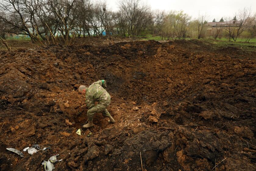Kramatorsk, Ukraine-APRIL 18, 2022-A Ukrainian soldier digs up fragment left by the missile that struck the town of Kramatorsk early Monday morning, April 18, 2022. (Carolyn Cole / Los Angeles Times)