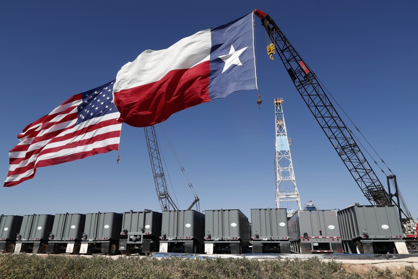 A U.S. flag and a Texas flag fly from the tops of cranes
