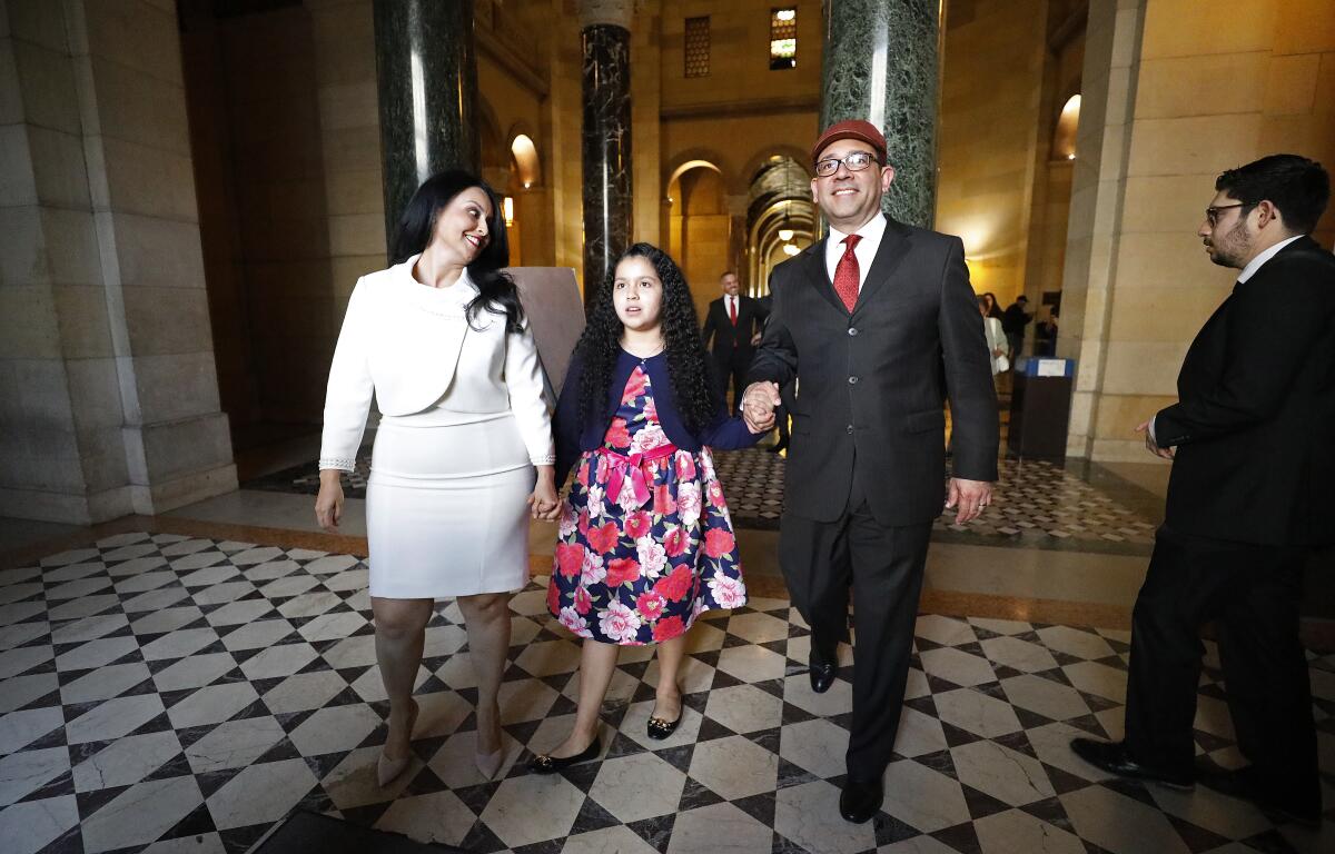 Husband Gerry Guzman, 10-year-old daughter Isabelle Guzman and Los Angeles City Council 6th district representative Nury Martinez walk out of Council Chambers to an outdoor reception following an address by Martinez to a crowded city council chambers.