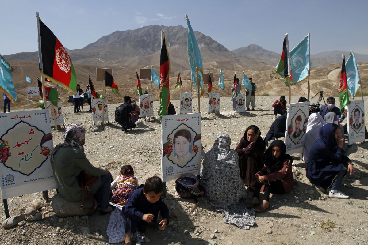 Families gather at the graves of their relatives, adorned with their pictures, on the outskirts of Kabul, Afghanistan, Monday, Sept 14, 2020. Scores of friends and families of students who were killed in local conflicts are gathering in a cemetery to call for a permanent countrywide ceasefire from the parties to the intra-Afghan peace conference taking place in Doha, Qatar. (AP Photo/Rahmat Gul)