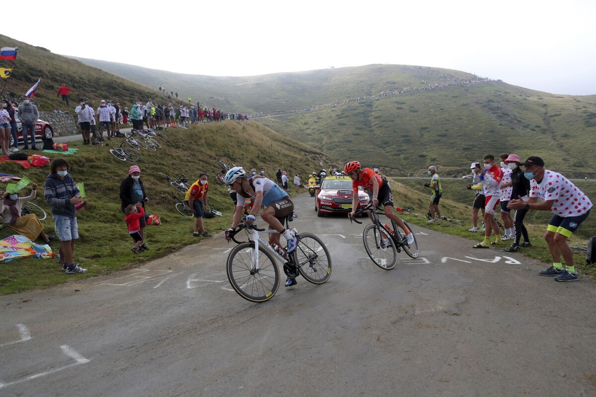 A spectator cheers France's Nans Peters, left, and Ilnur Zakarin of Russia as they climb Port de Bales pass during the stage 8 of the Tour de France cycling race over 141 kilometers (87.6 miles) from Cazeres-sur-Garonne to Loudenvielle, France, Saturday, Sept. 5, 2020. (AP Photo/Thibault Camus)