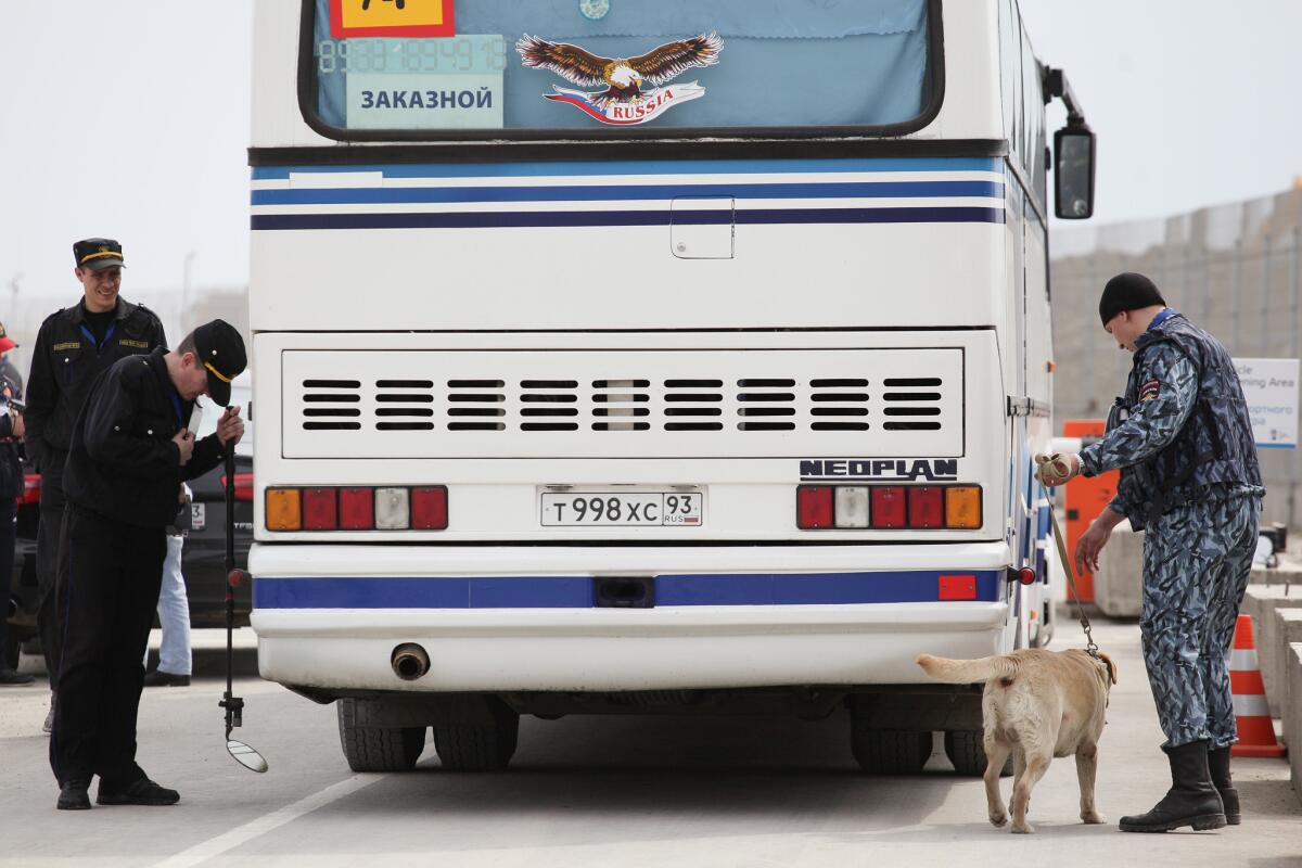 A police officer with a dog and security guards check a bus on April 16 entering the Olympic Park that is under construction for the 2014 Winter Games in the Black Sea resort of Sochi, Russia.