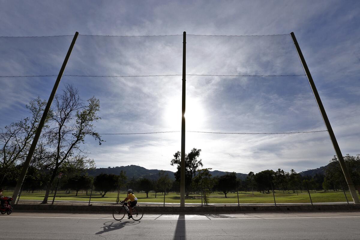 A bicyclist makes his way down Rosemont Avenue against a backdrop of the Brookside Golf & Country Club in Pasadena.