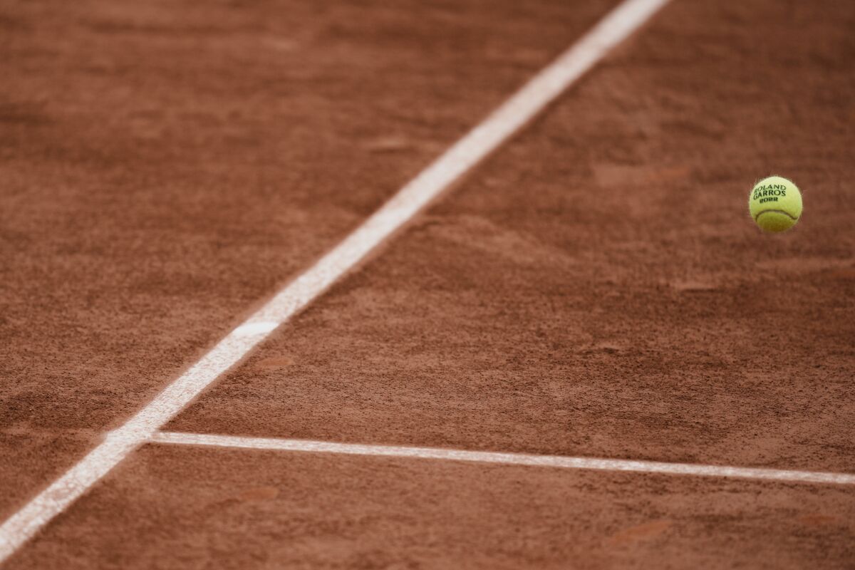 FILE - A Roland Garros 2022 ball flies over the clay court during a second round match at the French Open tennis tournament in Roland Garros stadium in Paris, France, Thursday, May 26, 2022. The French Open is the only Grand Slam tournament held on clay — which actually isn’t truly clay, but the dust from red brick on top of a layer of crushed white limestone. (AP Photo/Thibault Camus, File)