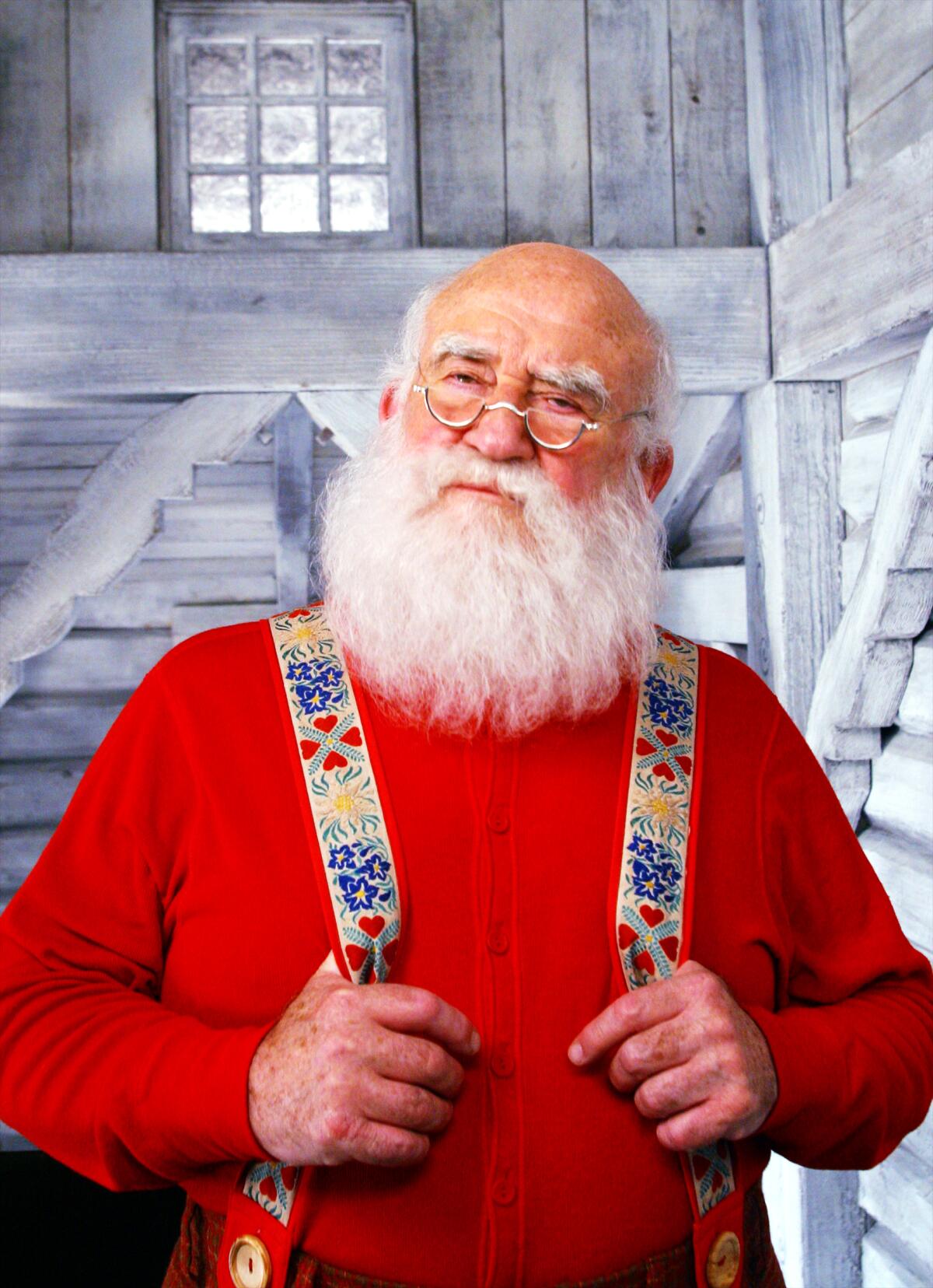 A man dressed as Santa Claus in a red shirt and colorful suspenders