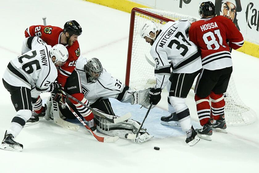 Kings defenseman Willie Mitchell, second right, tries to clear the puck out of the crease as Chicago Blackhawks forwards Bryan Bickell, second left, and Marian Hossa late in the third period of the Kings' 5-4 overtime win in Game 7 of the Western Conference finals.