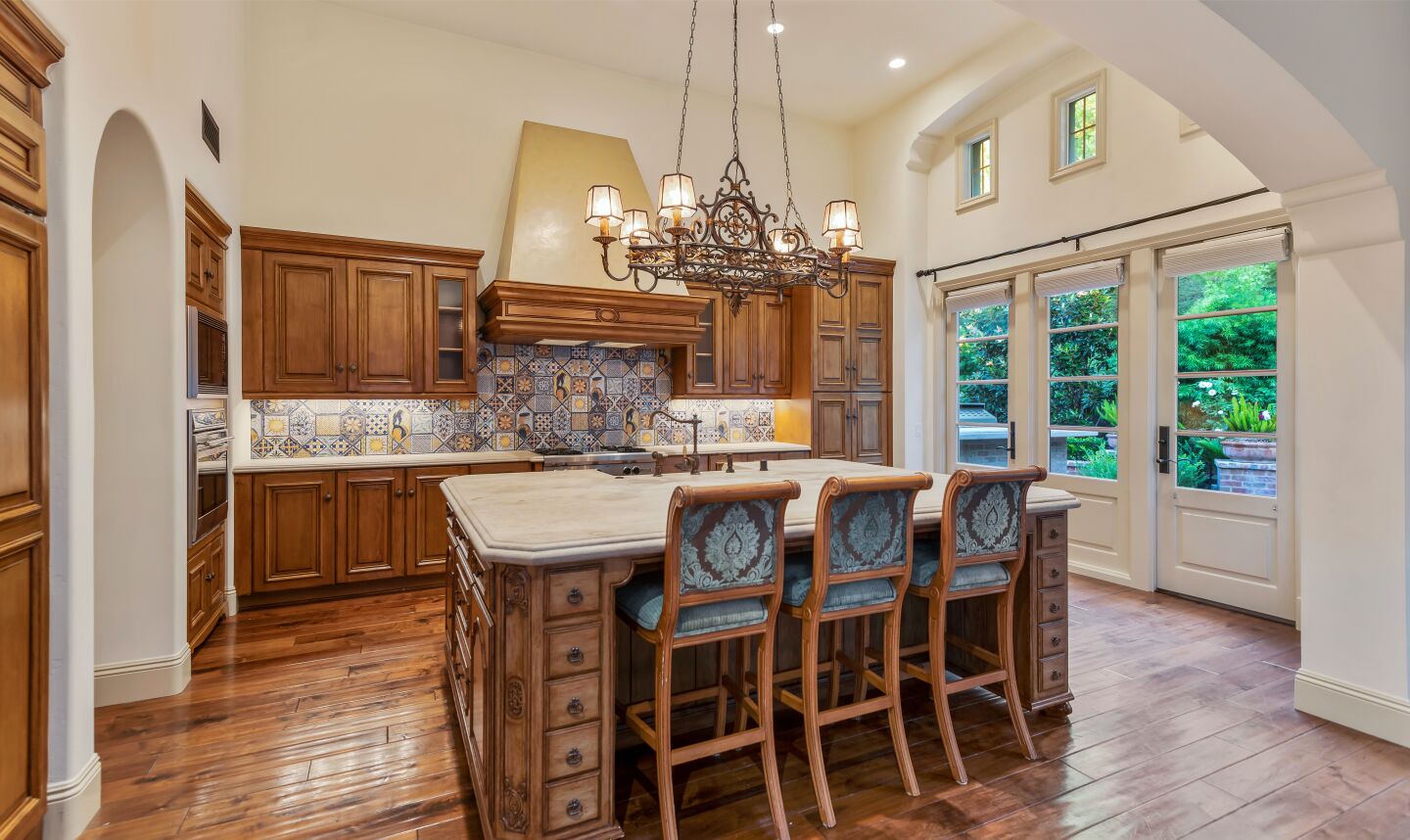 A dramatic chandelier, an island with limestone countertop and Spanish tile in the kitchen.