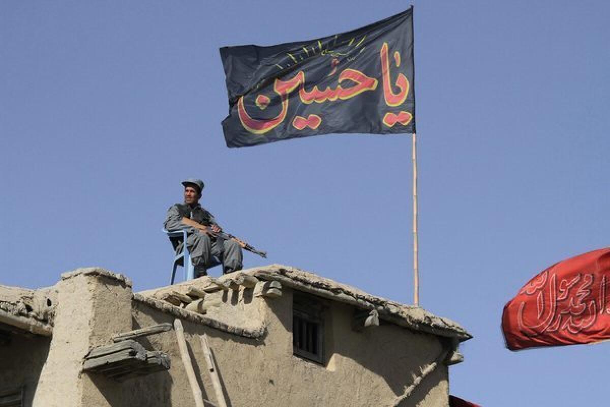 An Afghan policeman sits guard on a rooftop overlooking an Ashura procession in Kabul, Afghanistan.