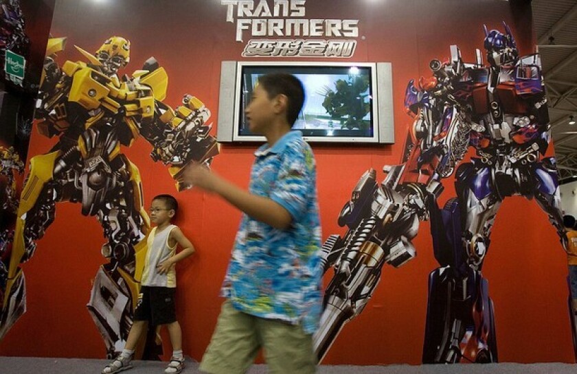 Chinese children pose for photos near an advertisement for the Hollywood movie "Transformers" during an animation fair held in Beijing in July 2007. The latest "Transformers" sequel has sold more than $159 million worth of tickets in China this summer.